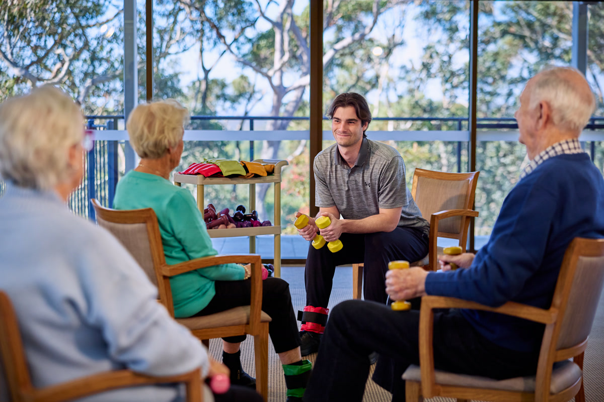 Reignite Health physiotherapist leading a small group exercise session with residents using dumbbells